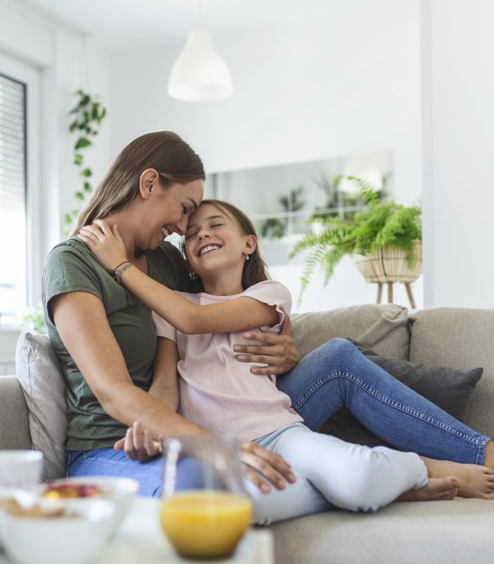 I love you so much. Portrait of happy young mother piggybacking cute smiling little daughter in living room, affectionate school age girl embracing beloved millennial female nanny or foster mom